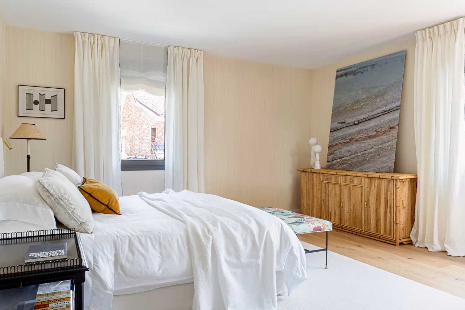 Dormitorio con cortinas de lino, cómoda de madera y gran cuadro en la reforma integral de Paseo de Alcobendas