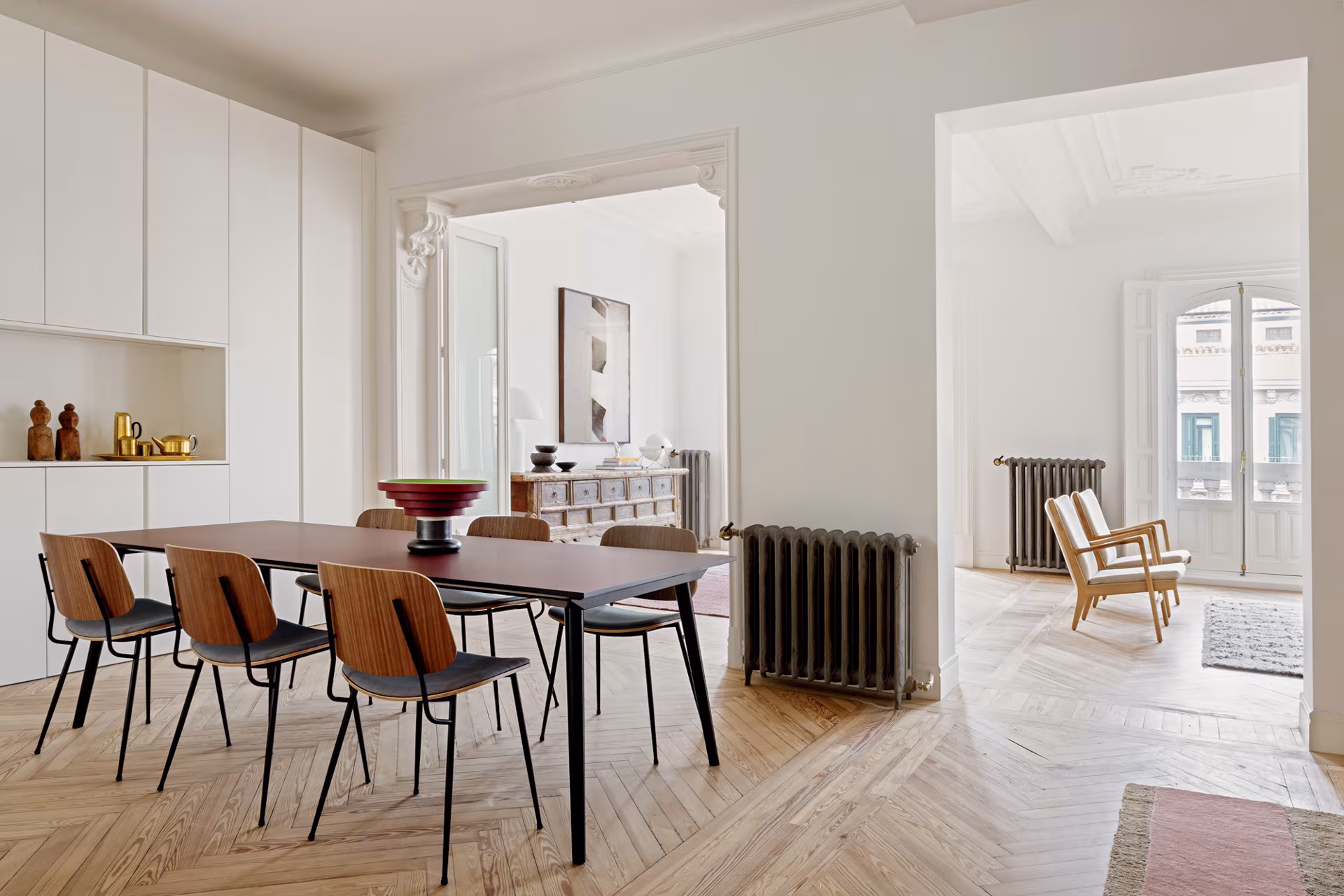 Dining room with dark wooden table and chairs, white cabinets and herringbone floor in Ábaton's Sagasta II refurbishment