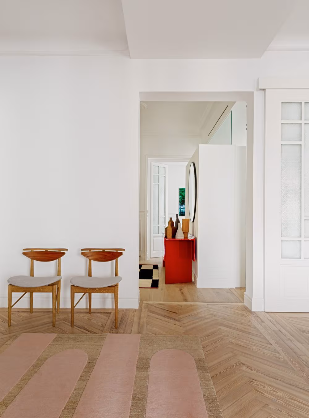 Herringbone parquet corridor with two wooden chairs and a red sideboard at the end in Sagasta II