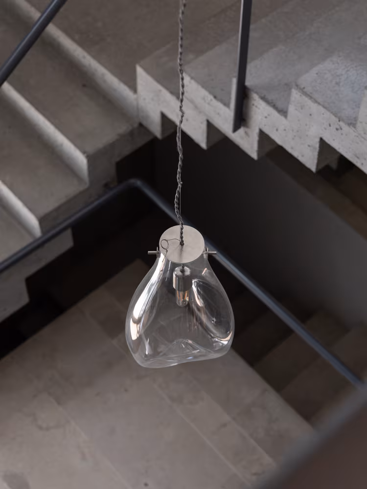 Blown-glass pendant lamp above a concrete staircase with a black railing