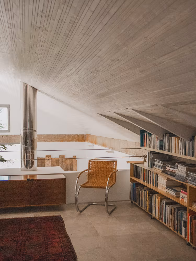 Study under a timber roof with bookshelves, a leather chair and a rug in an ÁBATON refurbishment
