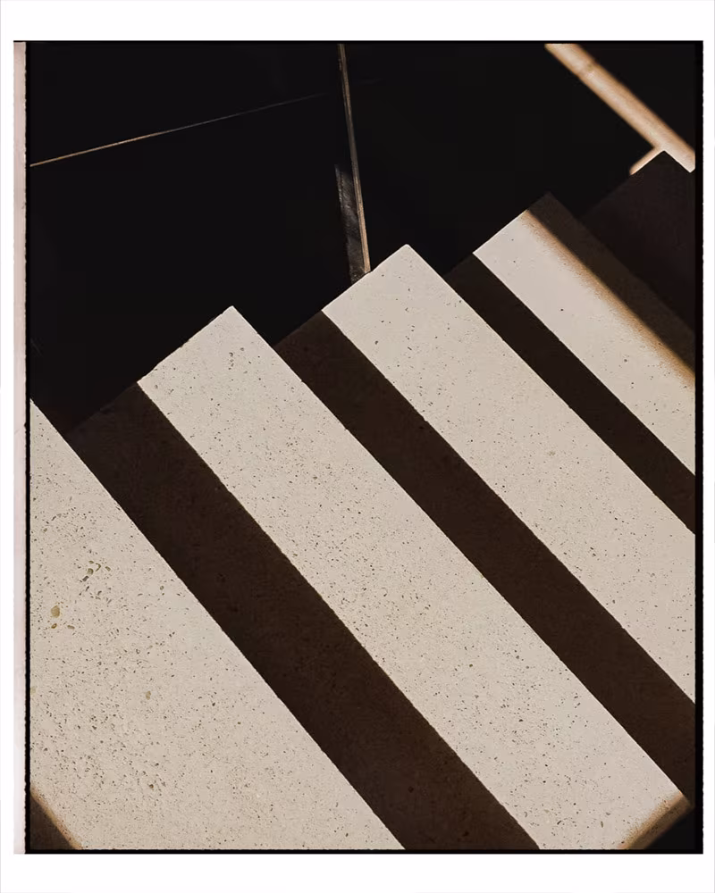 Pale stone steps with railing shadows on a staircase seen from above
