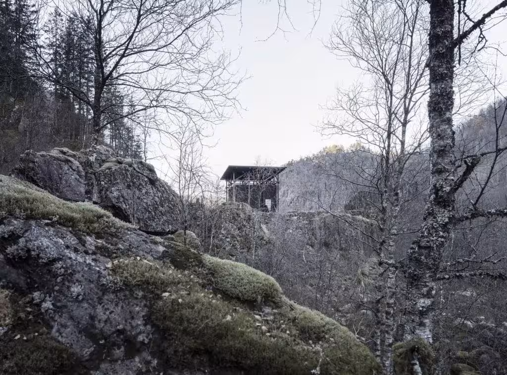 Dark pavilion of Peter Zumthor's Zinc Mine Museum among birches and rocks in Allmannajuvet, Norway