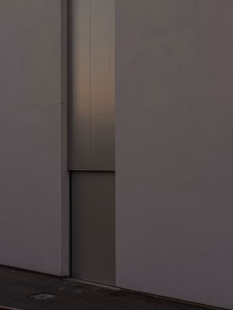 Detail of a white wall with a vertical metal joint in soft light at the CVNE winery
