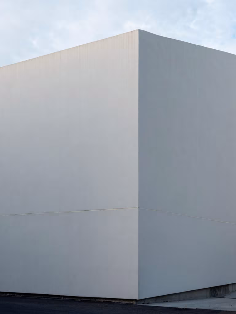 Corner of a smooth white volume against a pale sky in the CVNE winery complex