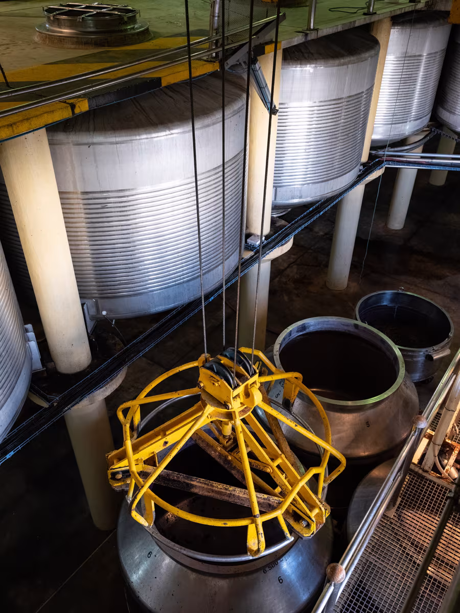 Stainless steel tanks and a yellow lifting basket in the winemaking area of the CVNE winery