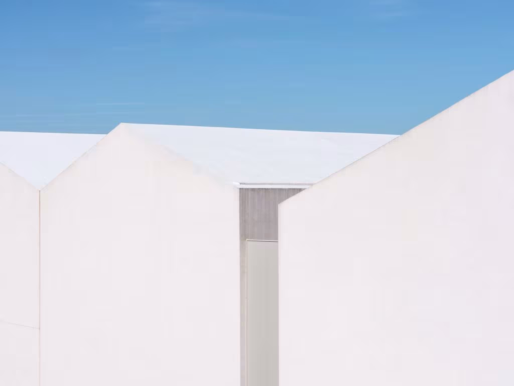 Cubiertas blancas a dos aguas contra un cielo azul en un detalle del proyecto ARV8 de Ábaton