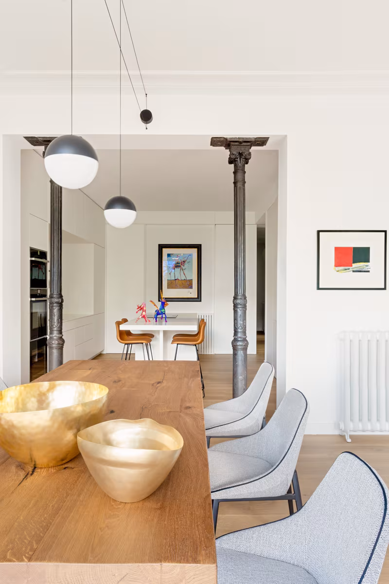Cocina-comedor al fondo con lámparas redondas, columnas de fundición y mesa de madera en Salesas de Ábaton