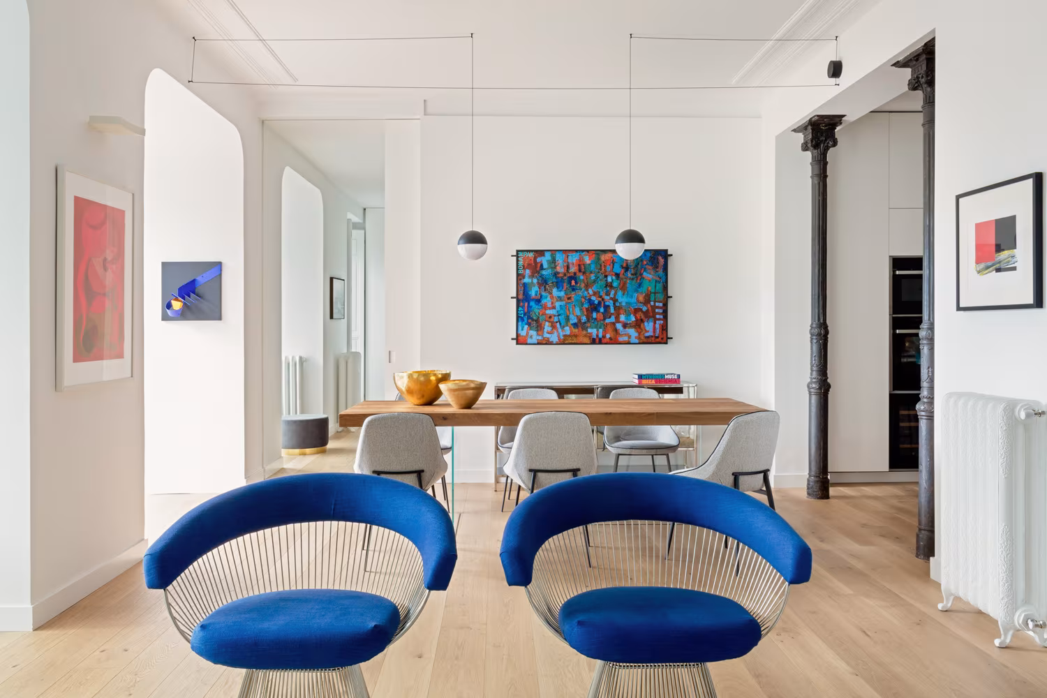 Comedor con mesa de roble, lámparas esféricas, columnas de hierro y butacas azules en Salesas de Ábaton