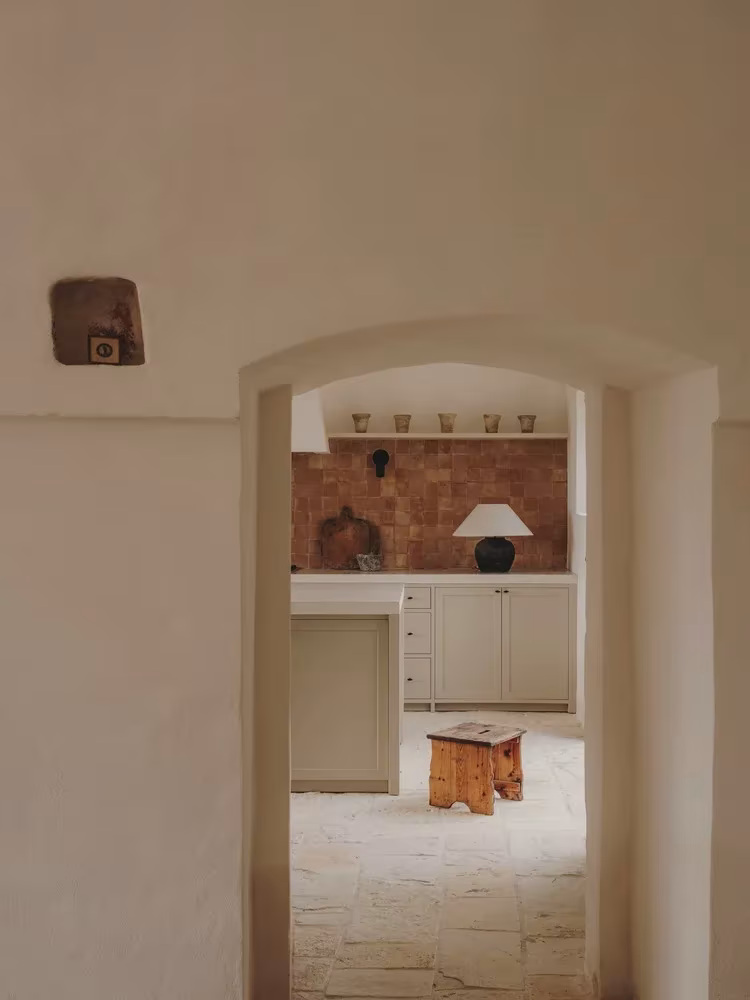 Arco encalado que enmarca la cocina de azulejos de barro con suelo de piedra en la Casa Casolare Scarani