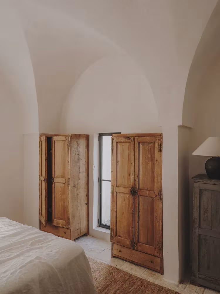 Dormitorio abovedado con armarios de madera antigua y ventana pequeña en la Casa Casolare Scarani