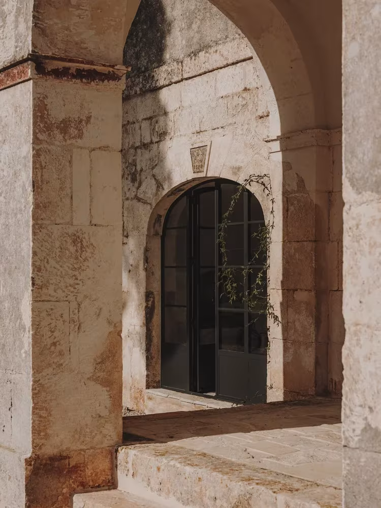 Portada de piedra con arco y carpintería metálica negra en la fachada de la Casa Casolare Scarani