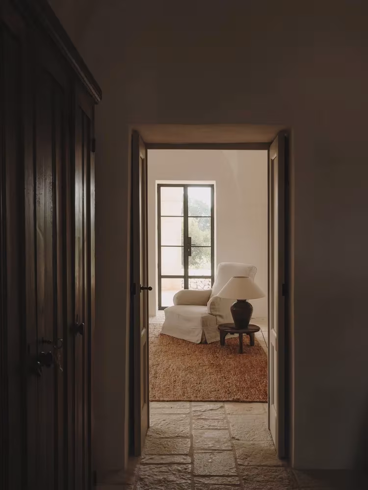 Puerta oscura abierta al salón luminoso al fondo de un pasillo de piedra en la Casa Casolare Scarani