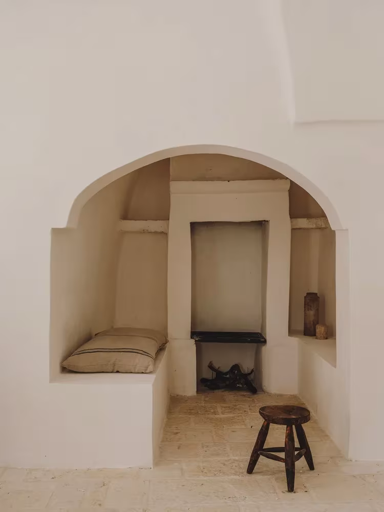 Hornacina encalada con banco de obra y taburete de madera, a modo de chimenea, en la Casa Casolare Scarani