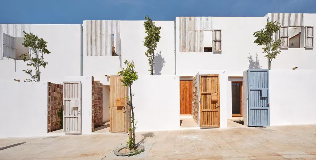 Viviendas encaladas con puertas de madera de colores alineadas en una calle del proyecto Life Reusing Posidonia