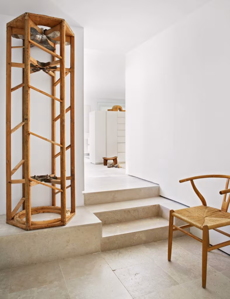 Vertical timber shelving unit beside stone steps and a cane chair, Casa Oviedo, Madrid
