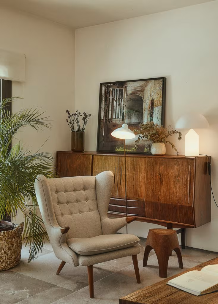 Walnut sideboard, upholstered armchair and large painting in a corner of the Casa Oviedo living room, Madrid