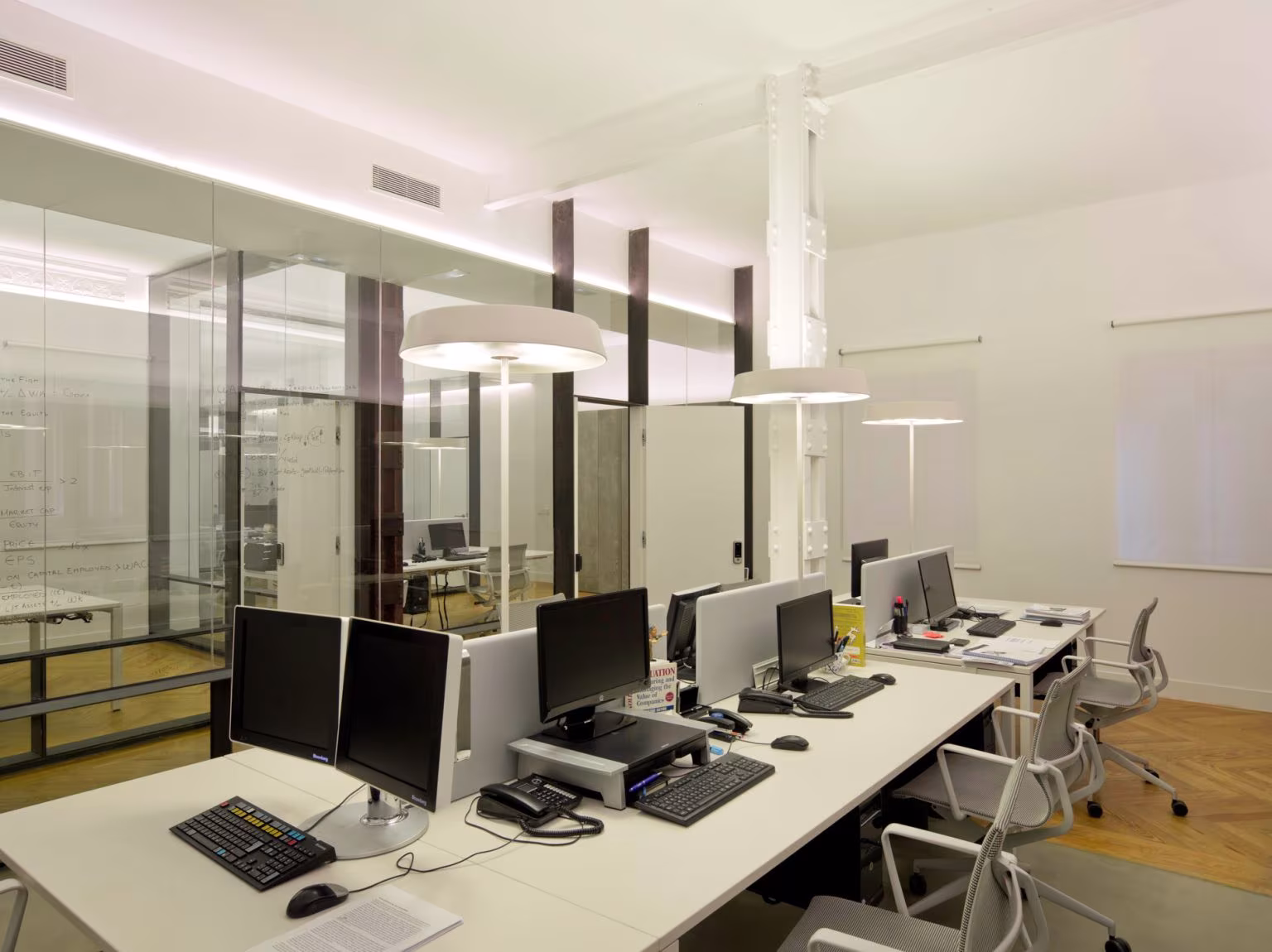 White desks with monitors under circular lamps and glass partitions, Oficina ED, Madrid
