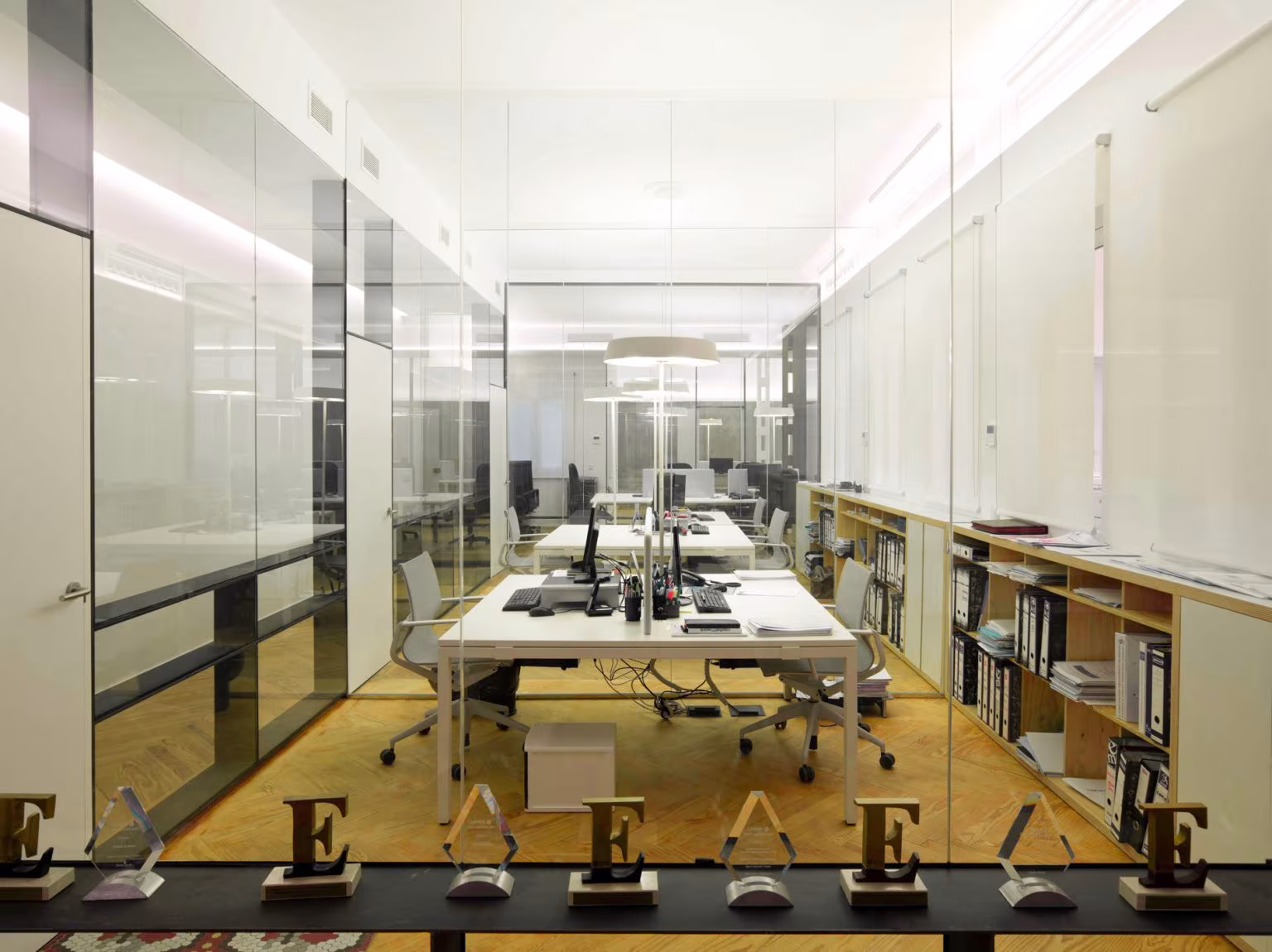 Workstations lined up behind glass partitions with side bookcases, Oficina ED, Madrid