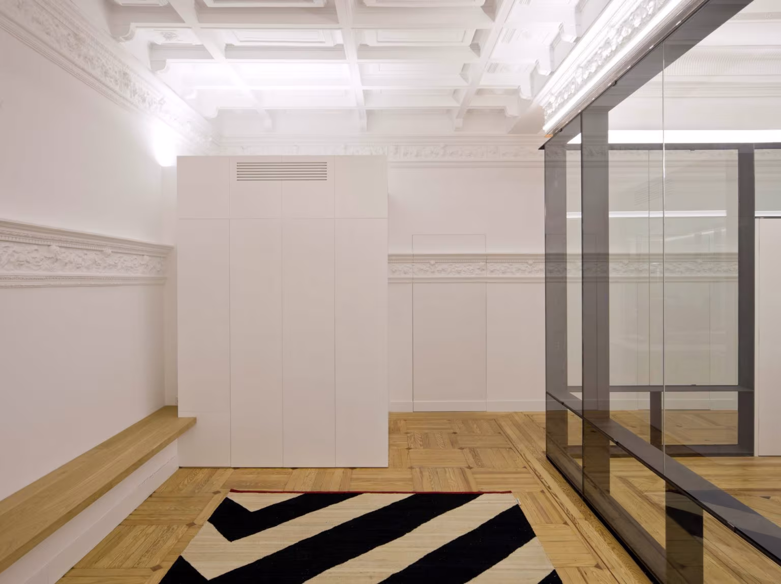 Room with white coffered ceiling, timber bench and black and white zigzag rug, Oficina ED