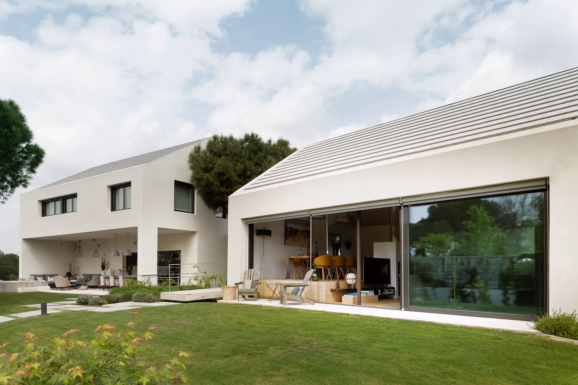 Rear façade of Proyecto XY with gabled roofs and a sliding window open to the lawn