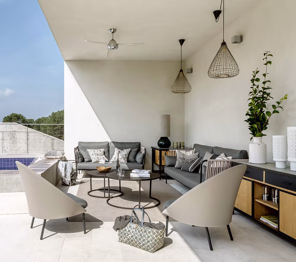 Porch with grey sofas, pale armchairs and side tables beside a timber unit and the pool