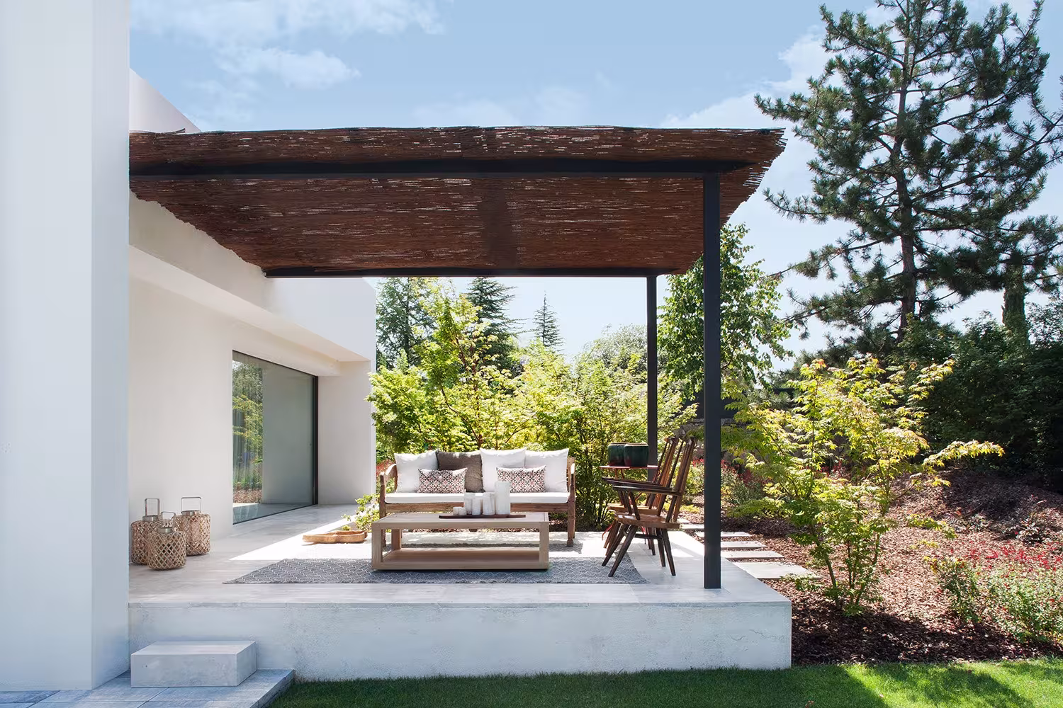 Porch with dark timber pergola on a metal post and a sofa and table set, La Moraleja refurbishment