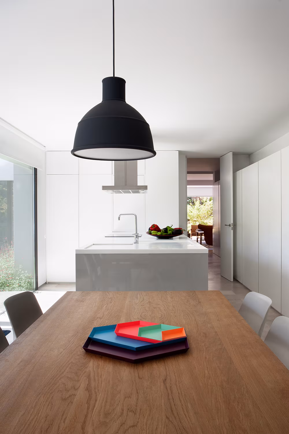 Oak dining table under a black pendant with the white-island kitchen beyond, La Moraleja refurbishment