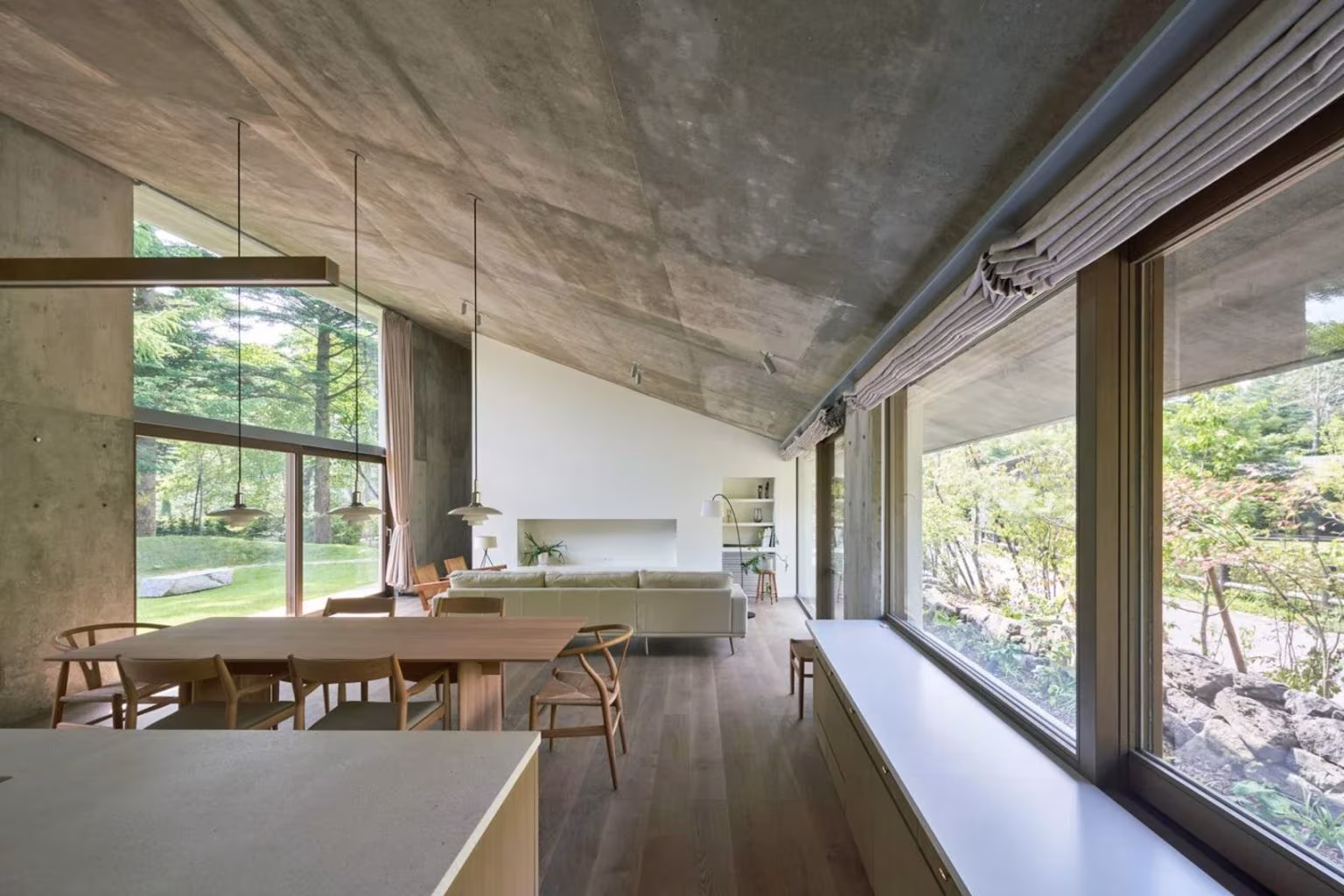 Dining and living area under the sloping concrete roof with large windows to the garden in the Symbiotic House