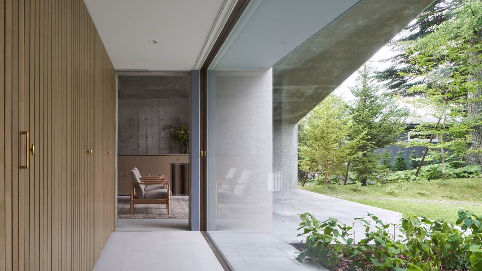 Gallery with timber slat panels and continuous glazing opening to the garden in the Symbiotic House