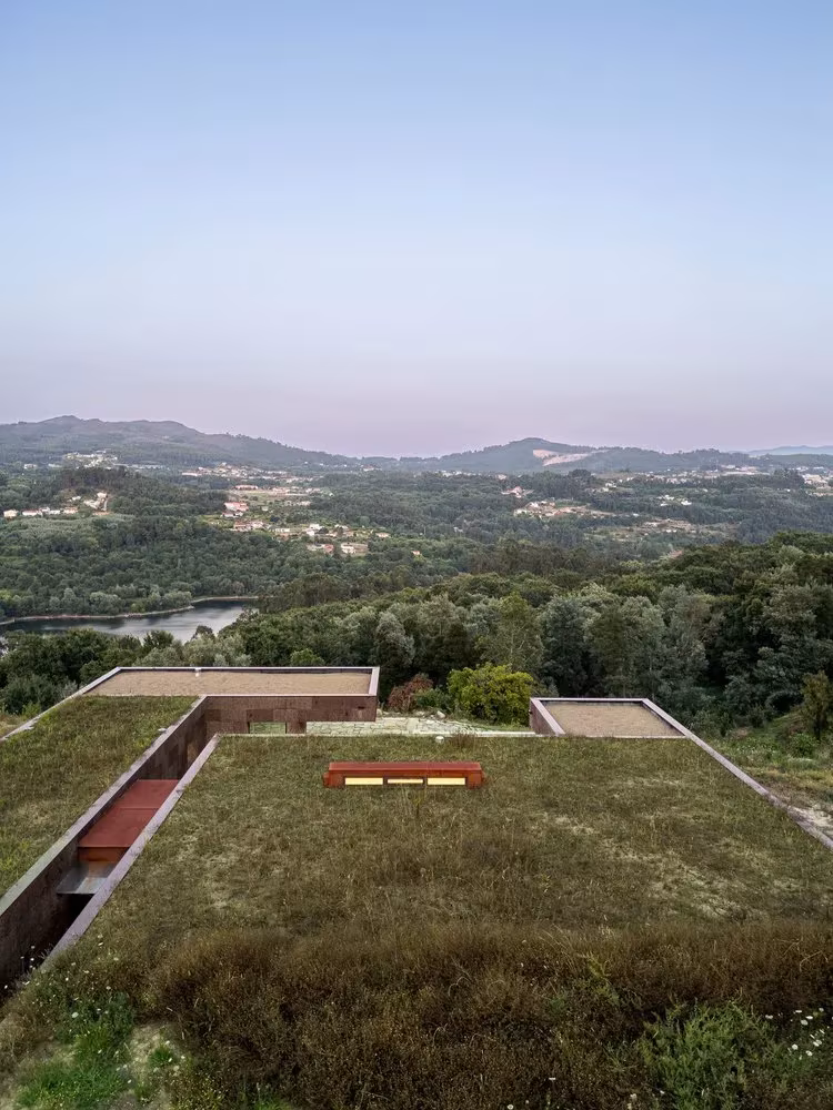 Casa da Levada al atardecer, con la cubierta vegetal y una banqueta de madera sobre el paisaje del valle