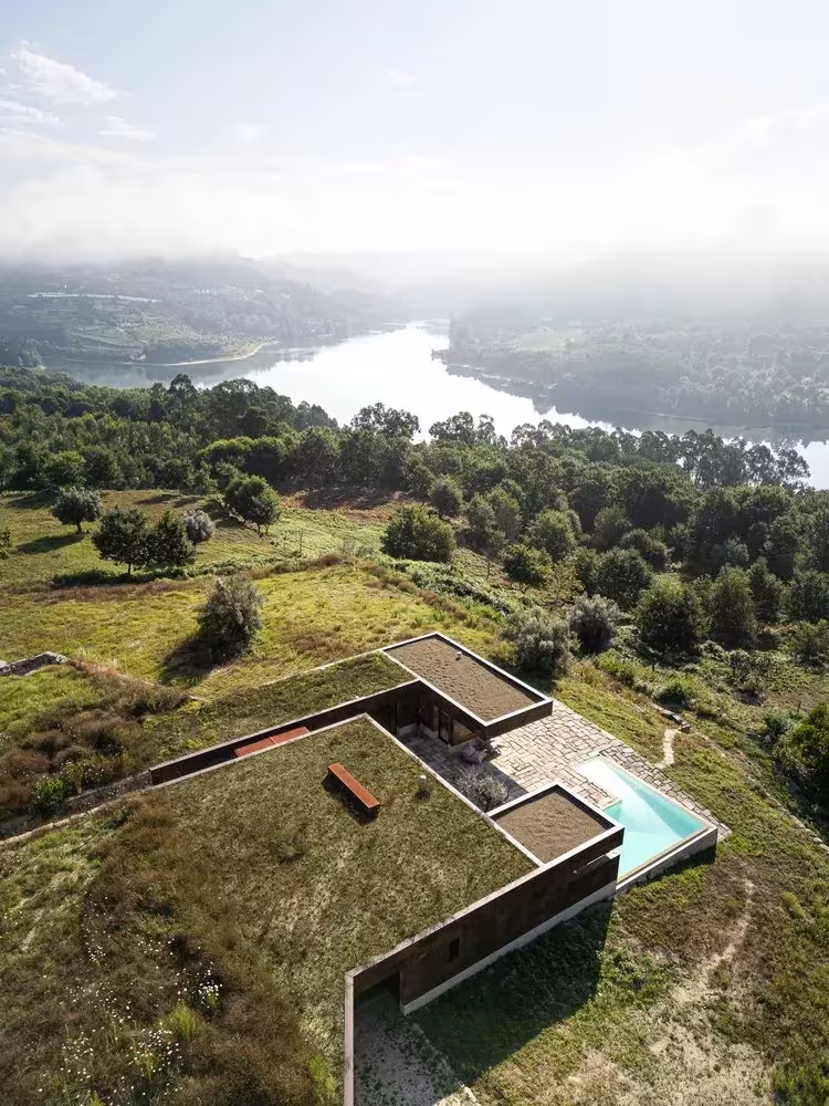 Casa da Levada hundida en la ladera sobre un meandro del río, con cubierta de vegetación y piscina