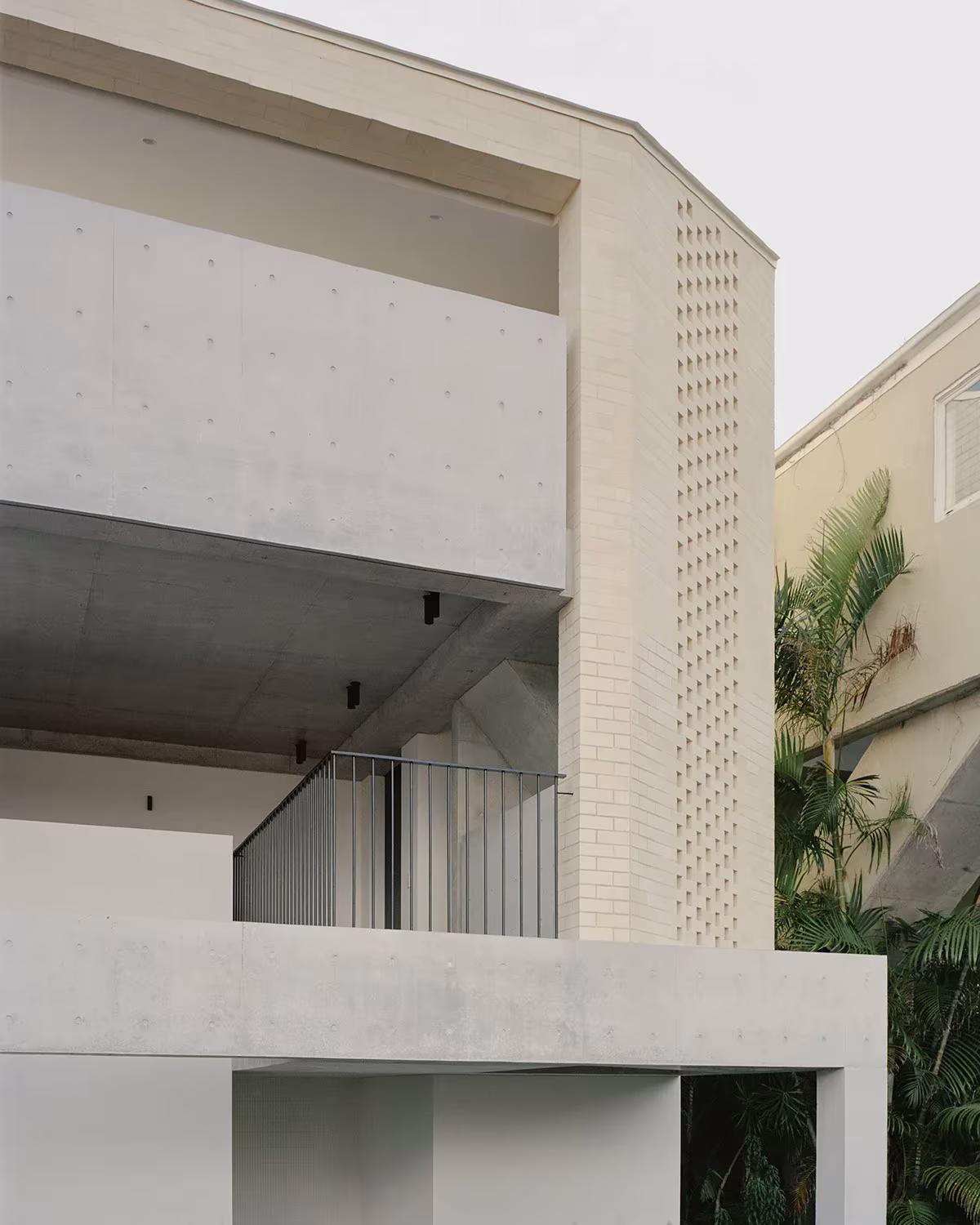 Detalle de la Bronte House con hormigón visto, celosía de ladrillo perforado y balcón de barandilla metálica