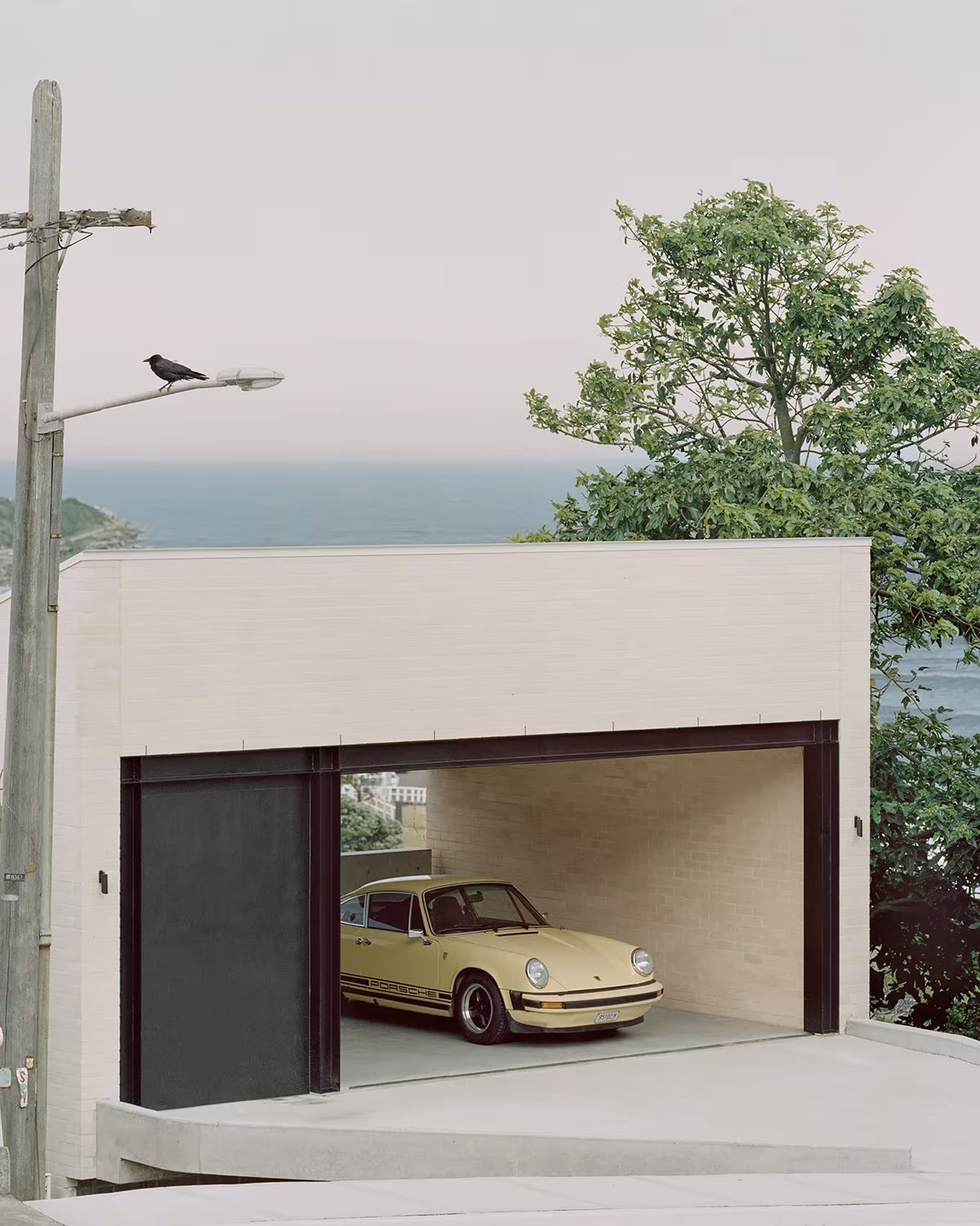 Garaje de la Bronte House con portón corredero, un coche clásico amarillo y el mar al fondo
