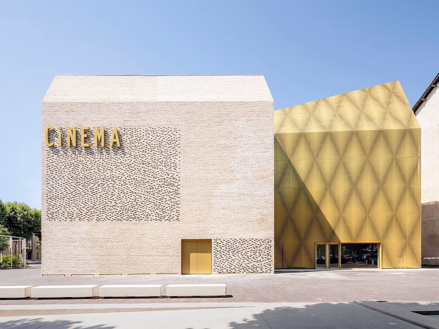 Le Grand Palais with the Cinema sign on pale brick and the golden diamond-pattern volume in Cahors