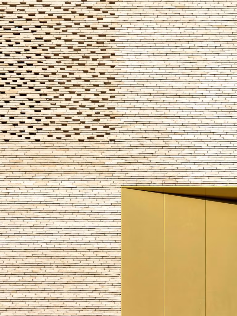 Detail of the perforated brickwork of Le Grand Palais with a golden metal door