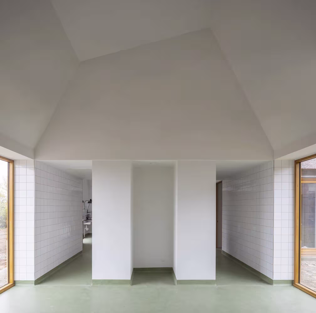 Sala de techo alto y paredes con azulejo blanco con volúmenes de armario centrales en Åstrup Have