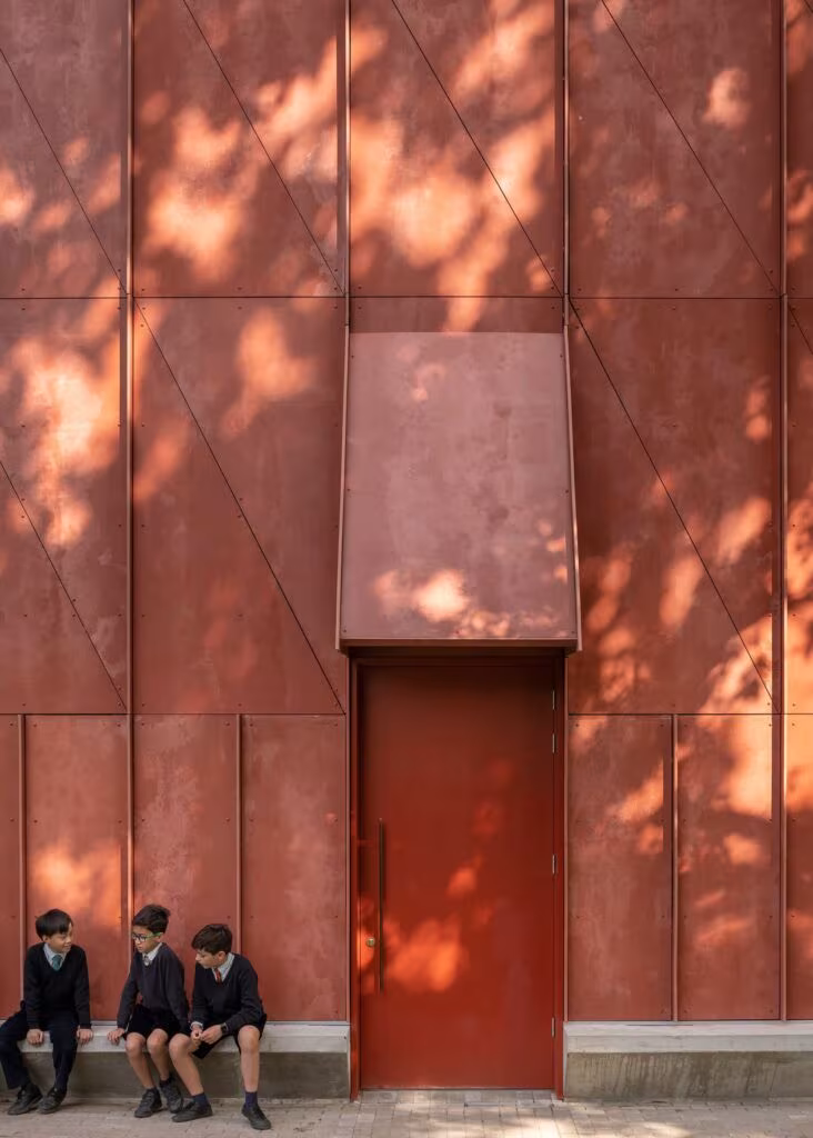 Entrance door under a metal canopy in the theatre's red facade, with children sitting in the shade
