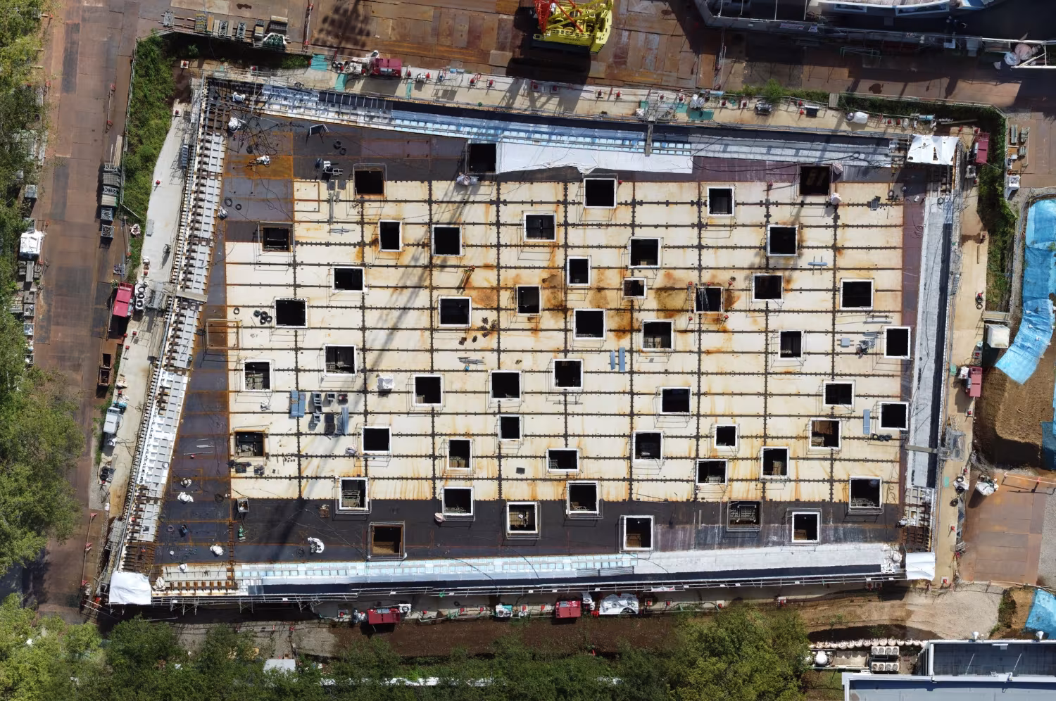 Vista aérea de la plaza KAIT en construcción, con la retícula de aberturas cuadradas en la cubierta