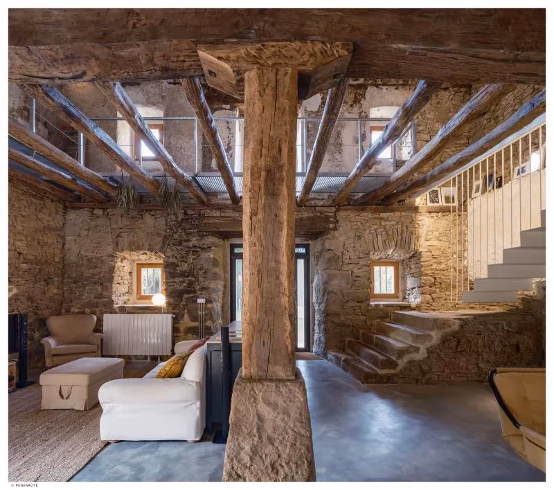 Pilar de madera de gran escuadría en el salón de Garaitia Etxea, con escalera blanca al fondo