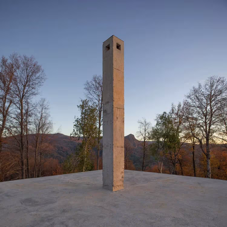 Chimenea esbelta de hormigón sobre la cubierta del Pabellón ROSA, entre árboles otoñales