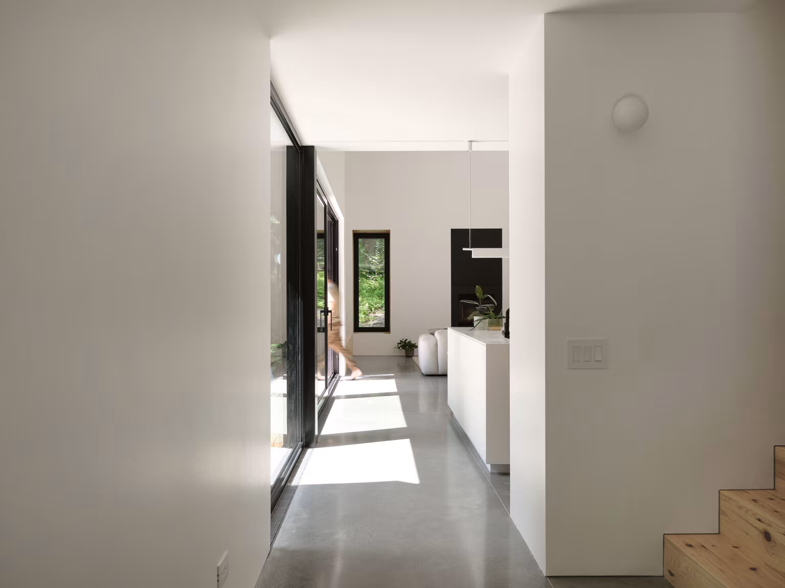 White corridor with raking light and a long window beside the pine stair, TISSARAOUATA