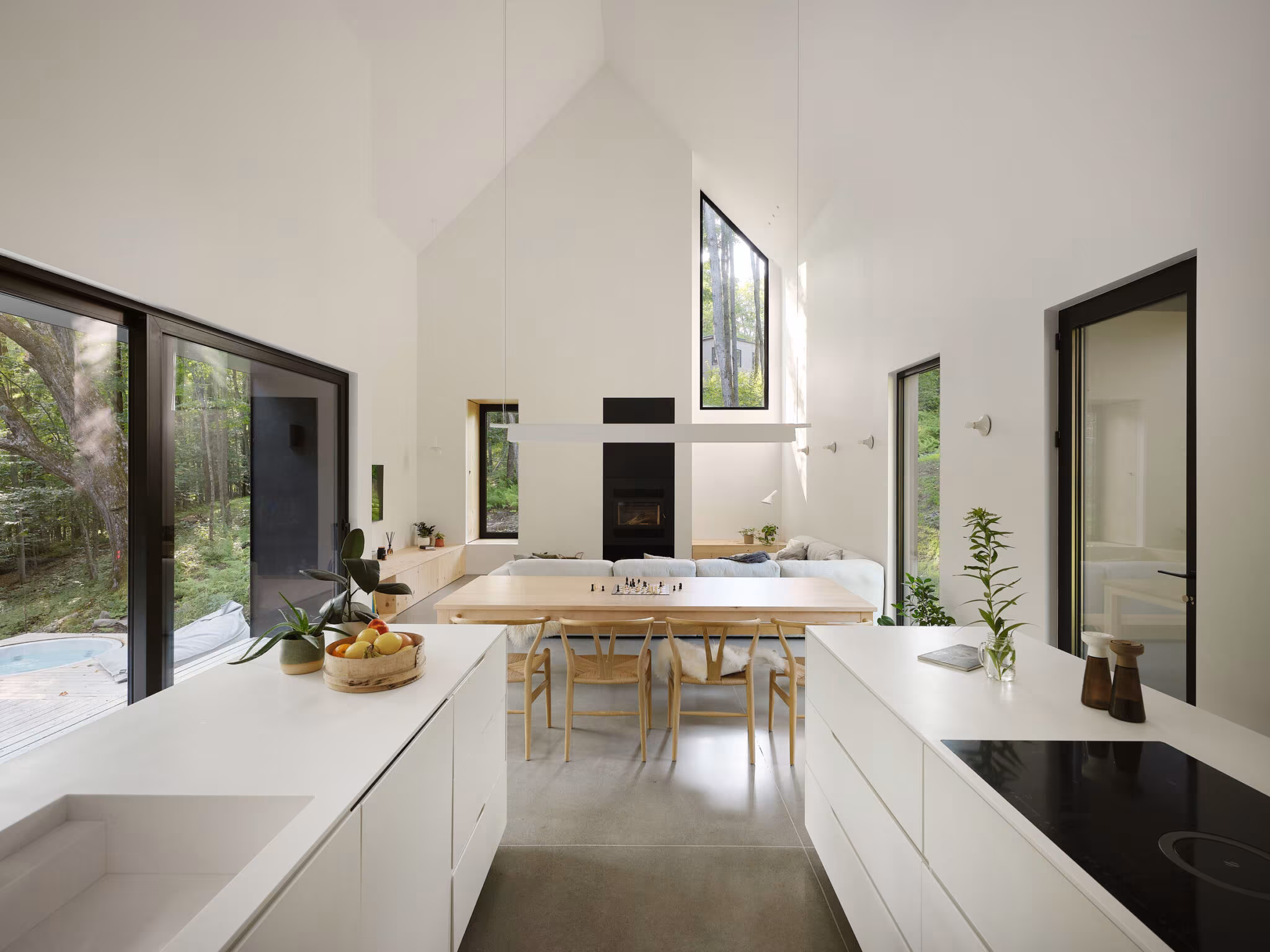 White kitchen and dining area with a high ceiling and large windows onto the forest, TISSARAOUATA