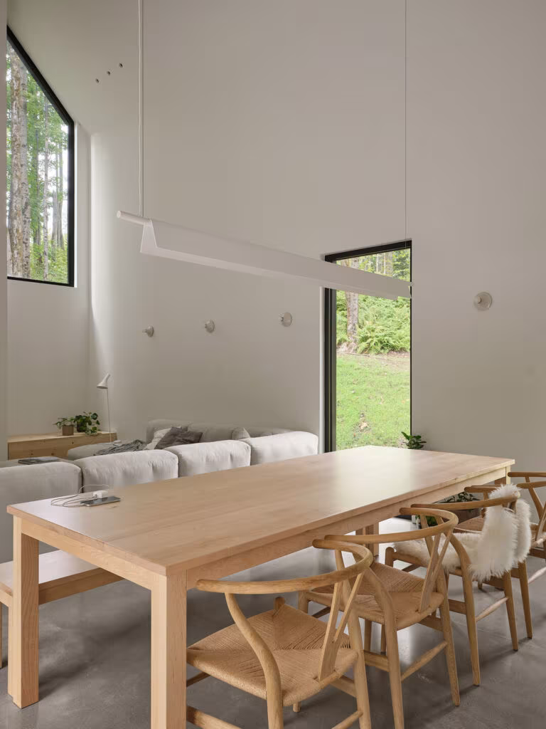 Pine table with timber chairs, sofa and a tall window in the dining room of TISSARAOUATA