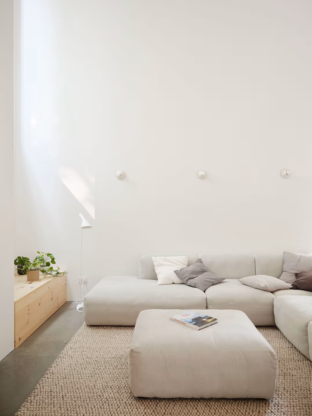Pale modular sofa, pouffe and fibre rug under the high ceiling of the living room, TISSARAOUATA