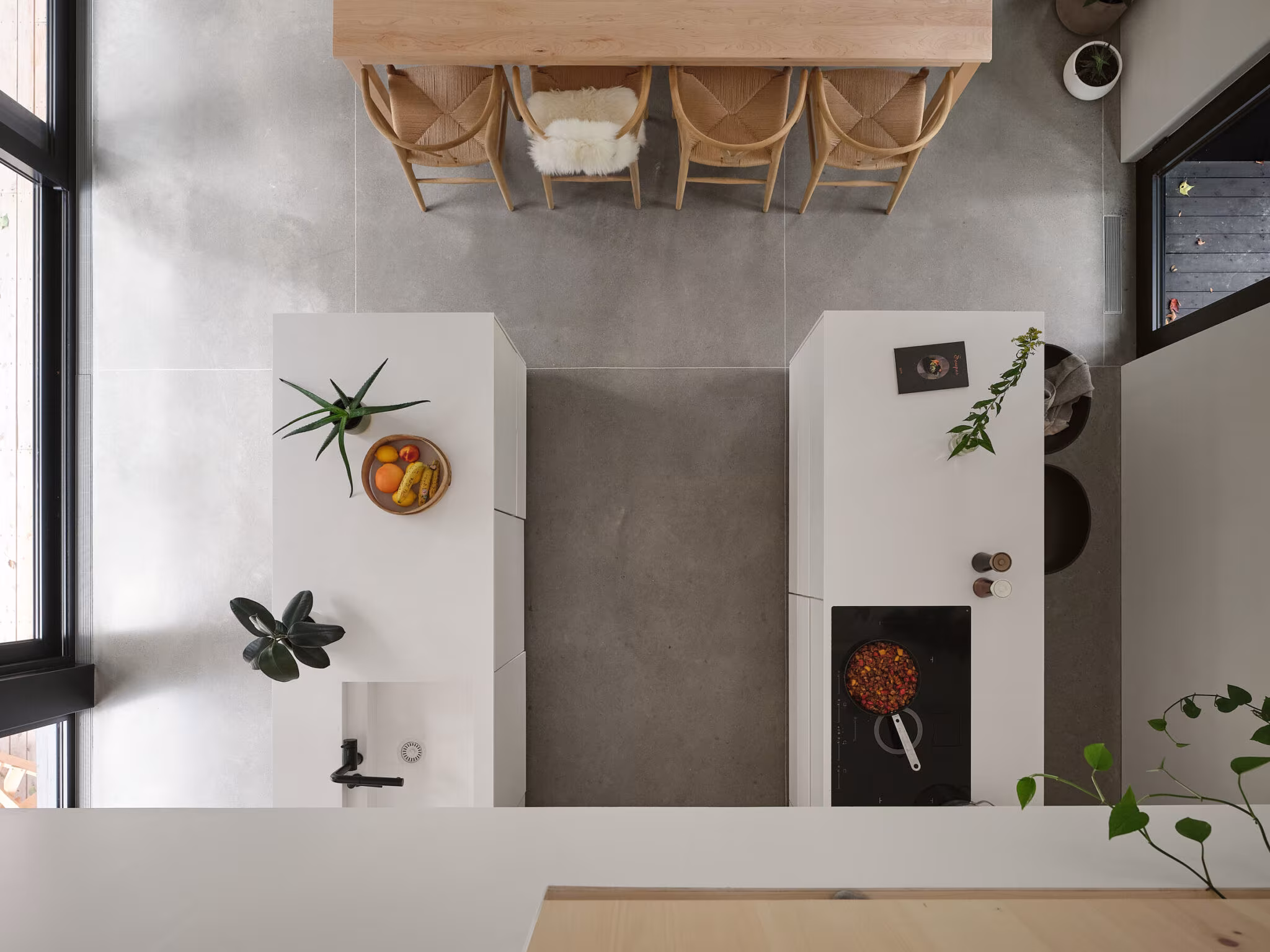 Overhead view of the white worktops, concrete aisle and dining table at TISSARAOUATA
