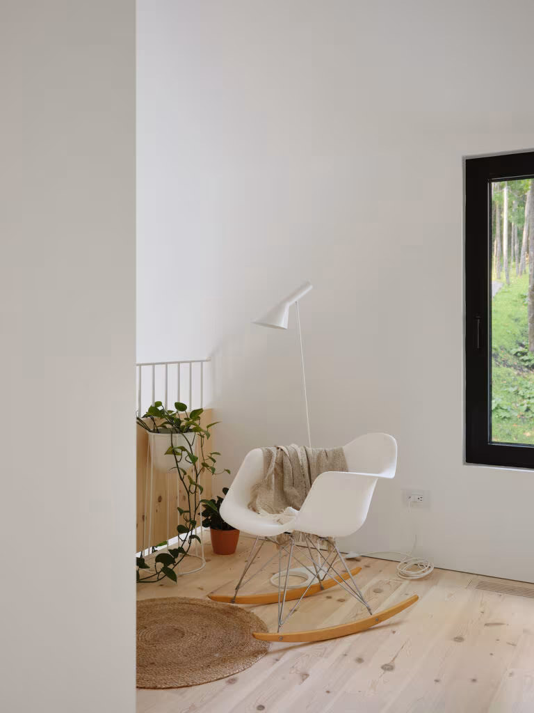 Reading corner with a white rocking chair and a window onto the forest, TISSARAOUATA