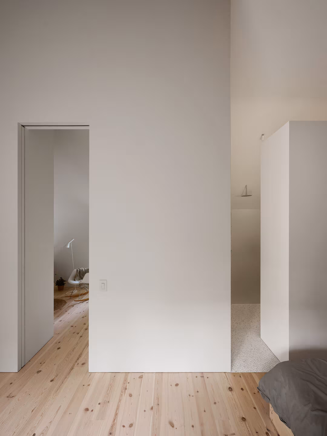 Sliding door open in a white partition over a pine floor leading to the bedroom, TISSARAOUATA