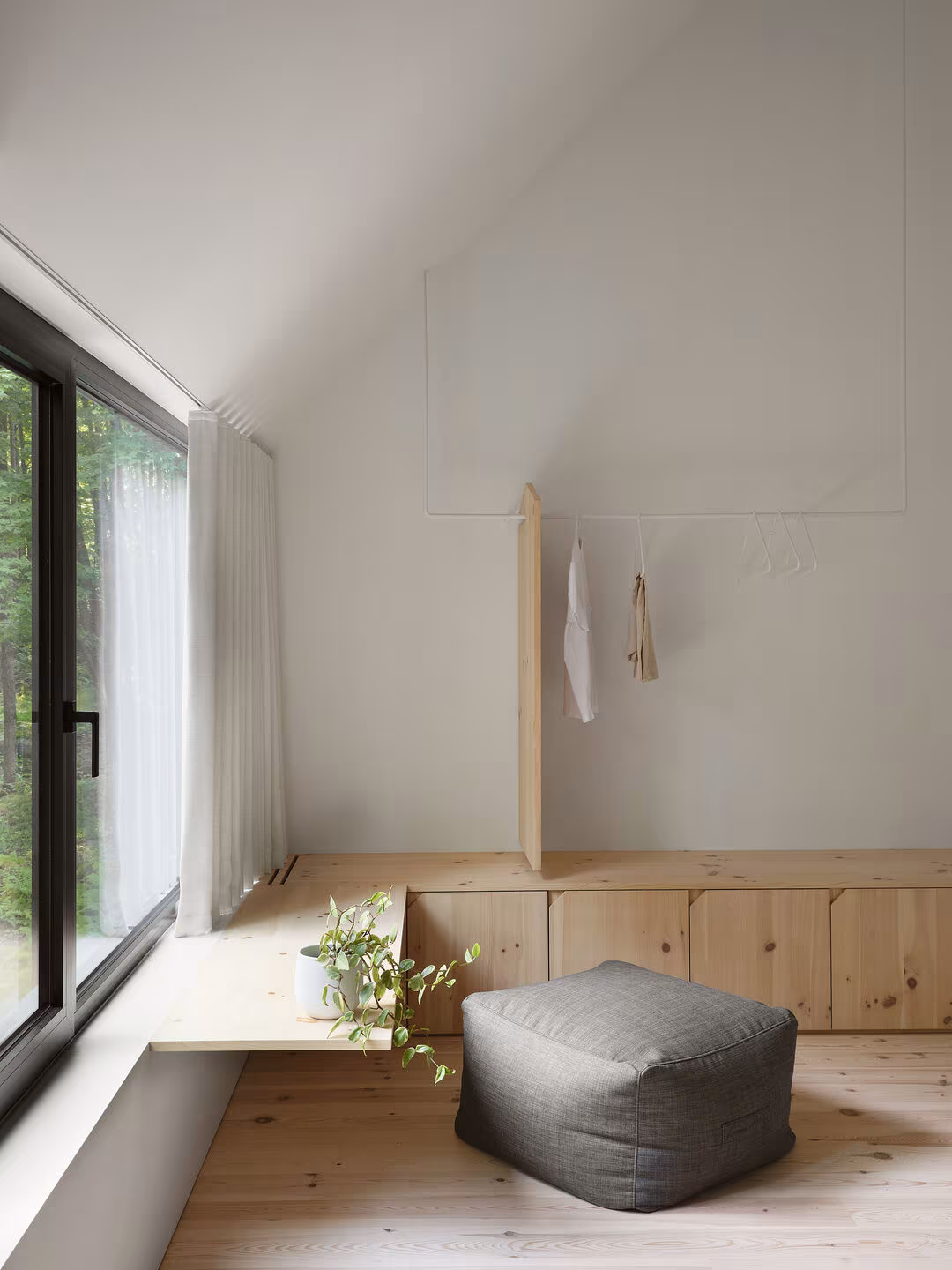 Rest nook with a pine window bench, grey pouffe and linen curtain at TISSARAOUATA