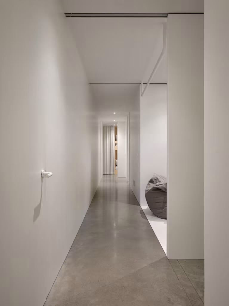 Long corridor with white walls and a polished concrete floor towards a play room, TISSARAOUATA
